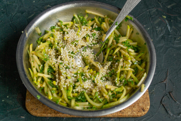 Sprinkling toasted white sesame seeds over the dressed salad
