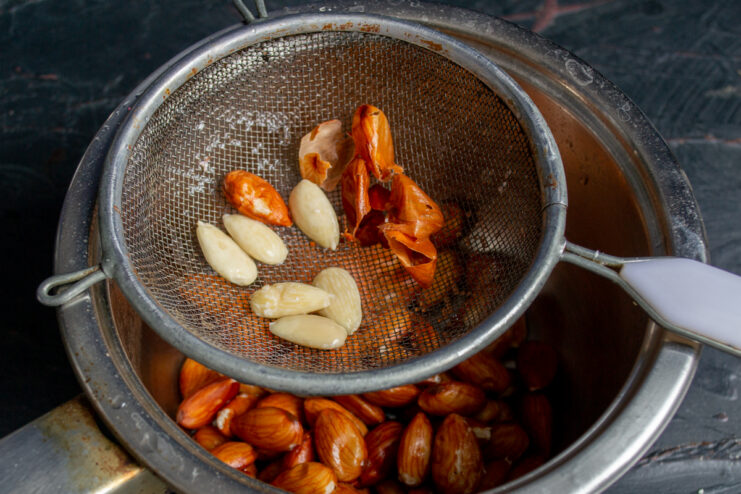 Squeezing a blanched almond to remove its brown skin
