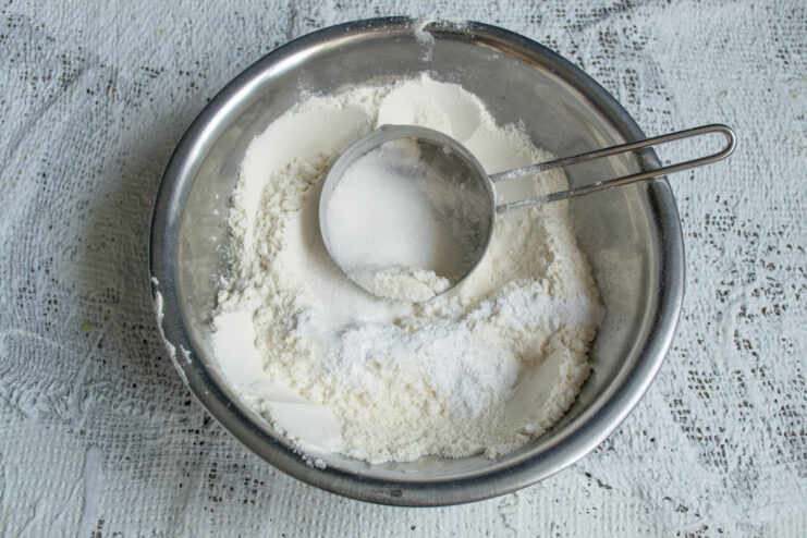Whisking dry ingredients Mixing flour, sugar, and baking powder together in a metal bowl