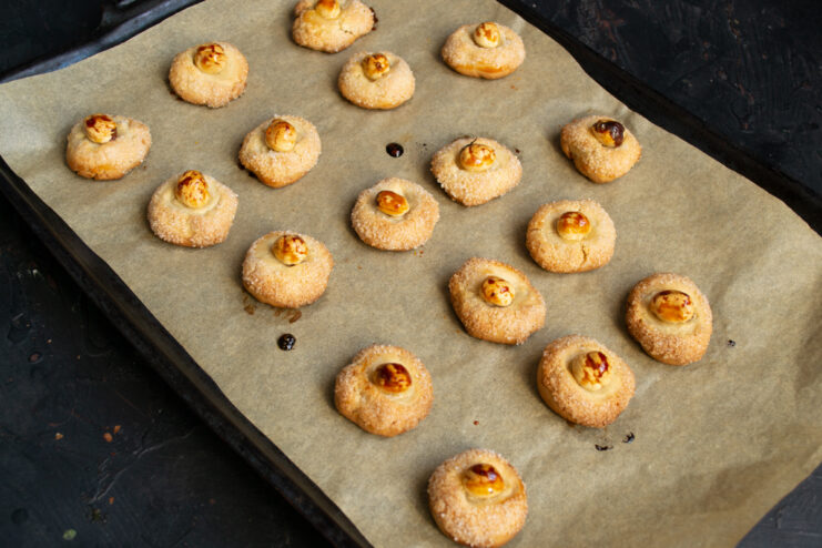 Baked cookies on sheet Baking sheet with baked golden cookies and nuts in the center.