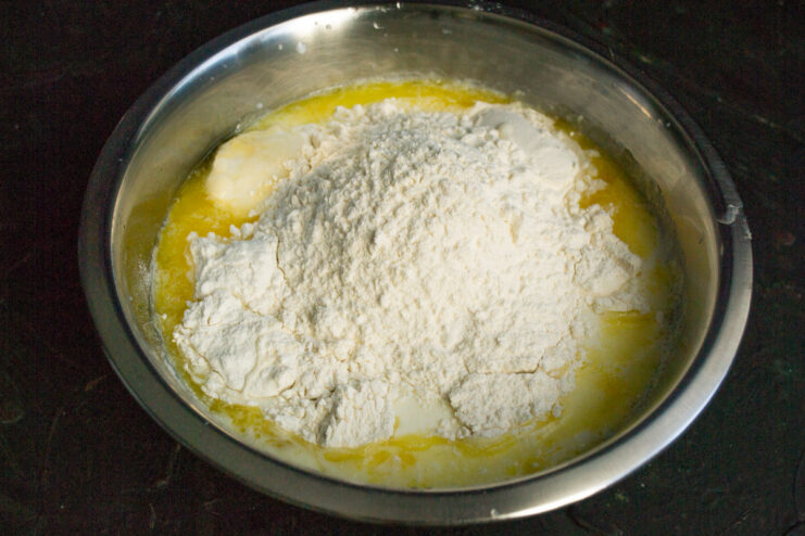 Wheat flour being poured into the liquid batter ingredients.