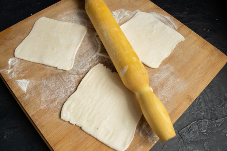 Rolled puff pastry cut into squares on a wooden board