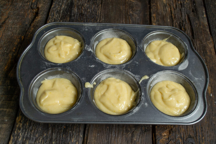 Filling the muffin cups Distributing thick batter into muffin tin compartments