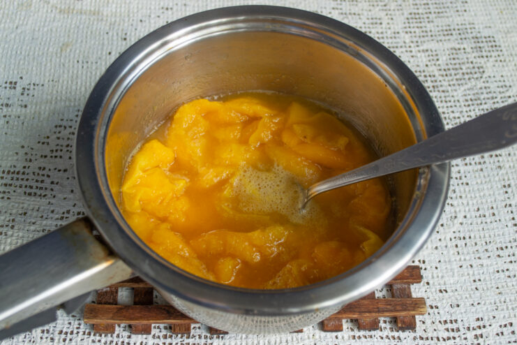 Simmering the apricots Softened apricot halves simmering in their own juices in a pot.