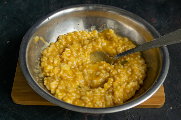Preparing the rice and vegetable base Rice filling mixed with sauteed vegetables and tomato puree in a metal bowl.