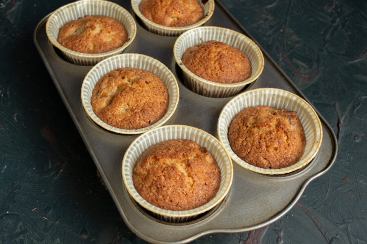 Baked muffins in the tin Golden brown baked muffins resting in a metal muffin tin.