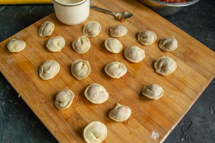 Freezing or cooking the shaped dumplings Rows of hand-shaped pelmeni arranged on a wooden surface