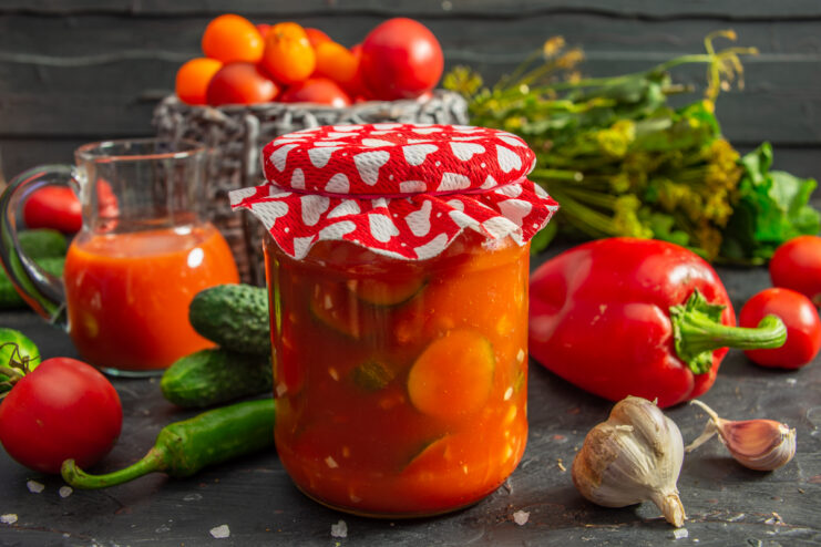 Glass jar of crispy winter cucumber salad in rich tomato sauce with garlic and bell peppers