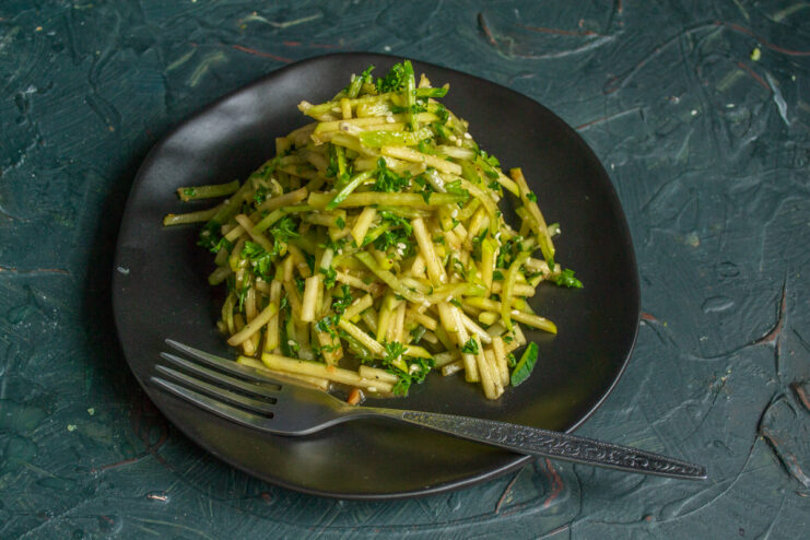 Appetizing green radish, apple, and cucumber salad on a serving plate