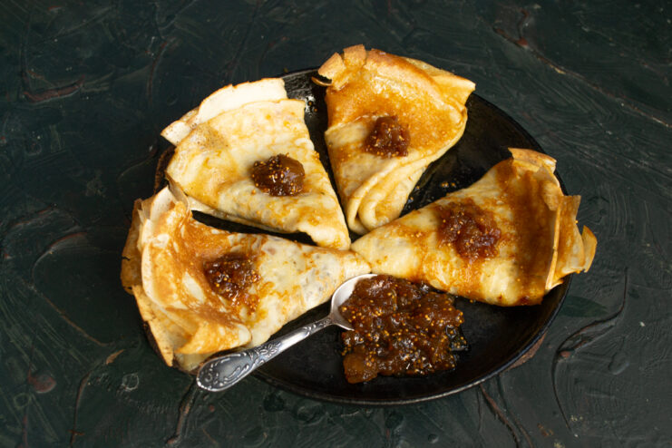 Plated French crepes drizzled with fig sauce.