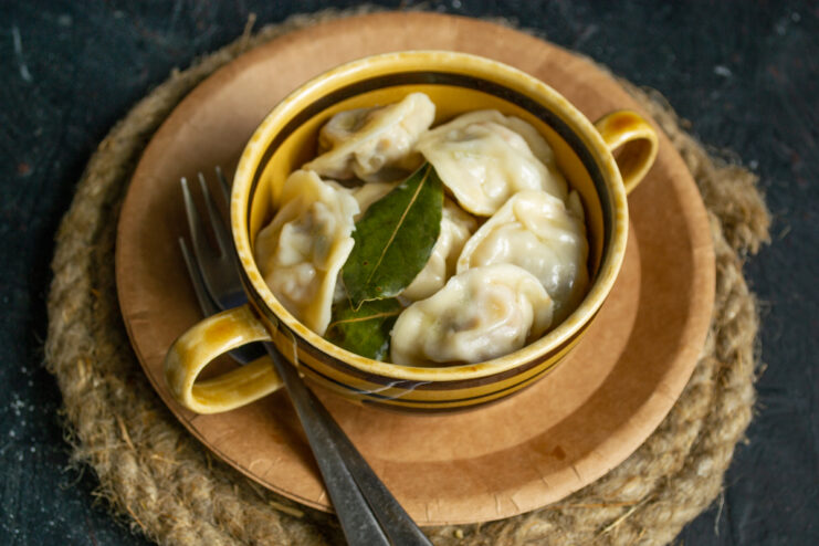 Serving hot pelmeni with butter and vinegar Plated pelmeni served in a deep bowl on a rustic surface