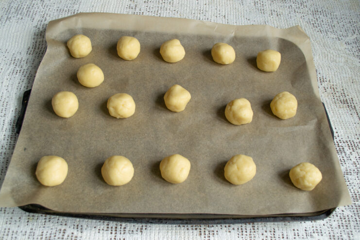 Shaping the cookies Small balls of shortbread dough on a parchment-lined baking sheet