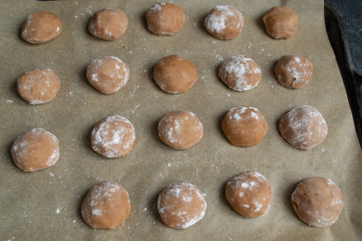 Shaping the Cookies Small chocolate dough balls on a parchment-lined baking sheet
