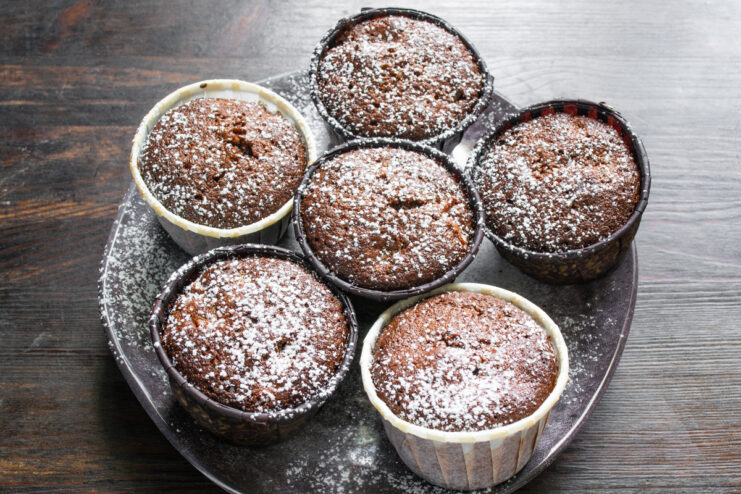 Finishing Touch Cooled chocolate cupcakes dusted with powdered sugar on a plate