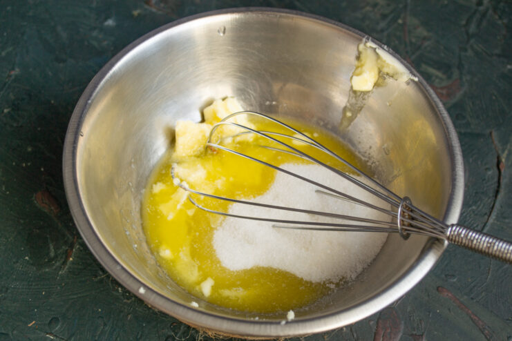 Mixing butter and sugar Softened butter, sugar, and a wire whisk resting in a mixing bowl.