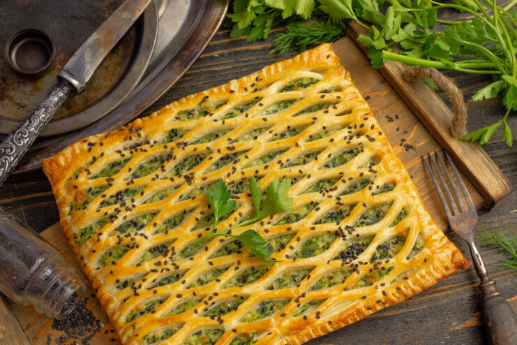Golden spinach and ricotta puff pastry tart with a crisp crust on a wooden board