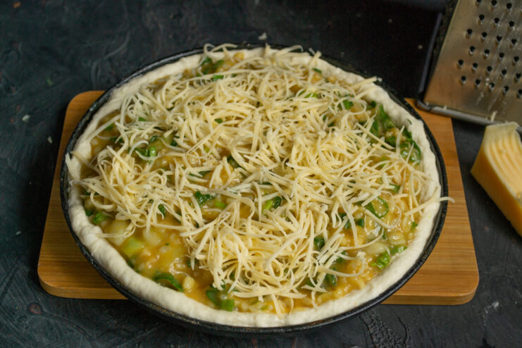 Topping with cheese Pie generously topped with grated cheese before baking in the oven.