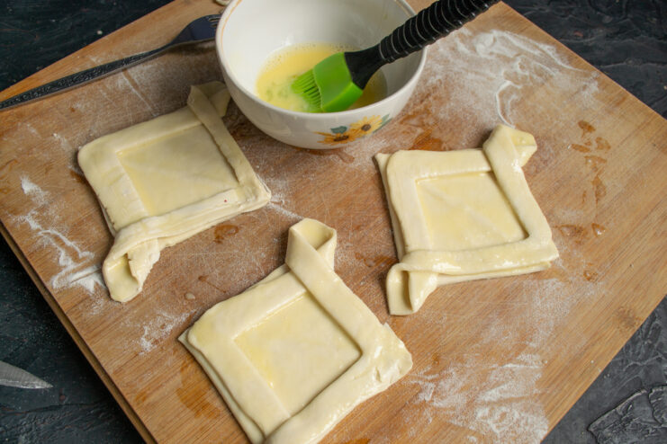 Brushing the shaped puff pastry pieces with beaten egg wash