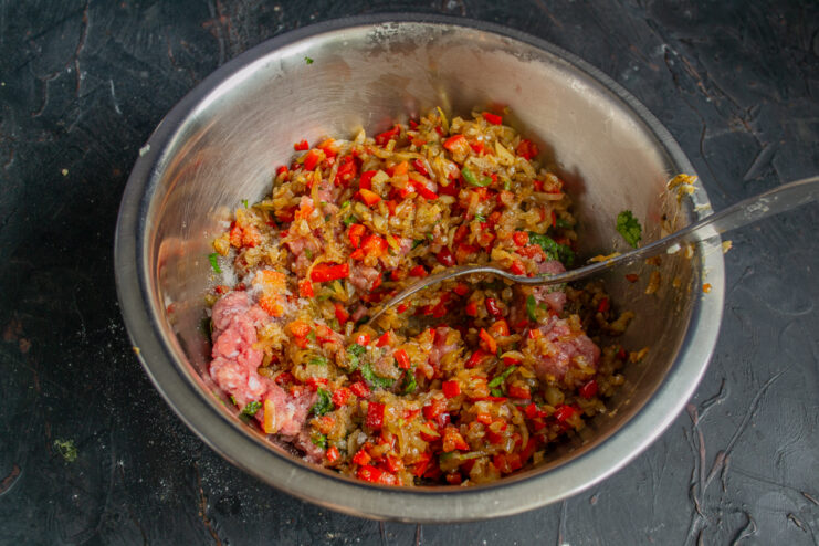 Combining the meat and vegetable mixture Mixing the ground meat with the sautéed vegetable blend