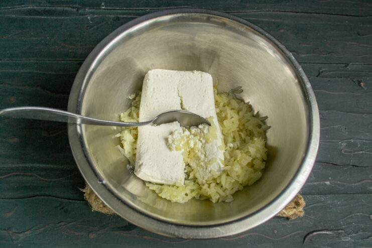 Mixing cheese and onion Mixing farmer's cheese with sautéed onions in a glass bowl