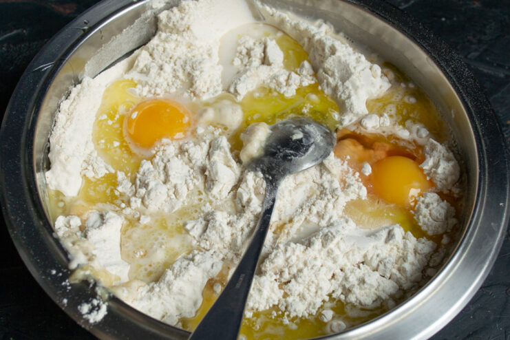 Mixing the dough Mixing eggs, flour, and milk in a bowl with a wooden spoon
