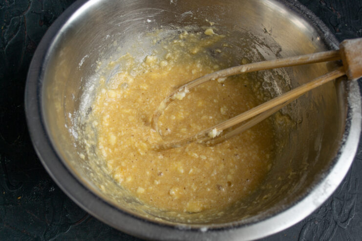 Whisking in Liqueur Whisking wet ingredients with Amaretto in a mixing bowl