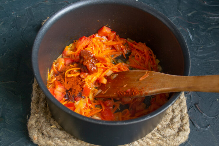 Adding spices and soybean paste Stirring soybean paste and paprika into the sauteed vegetables.