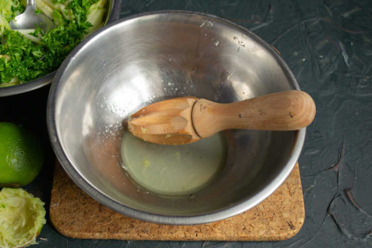 Straining fresh lime juice into a small bowl to make the dressing