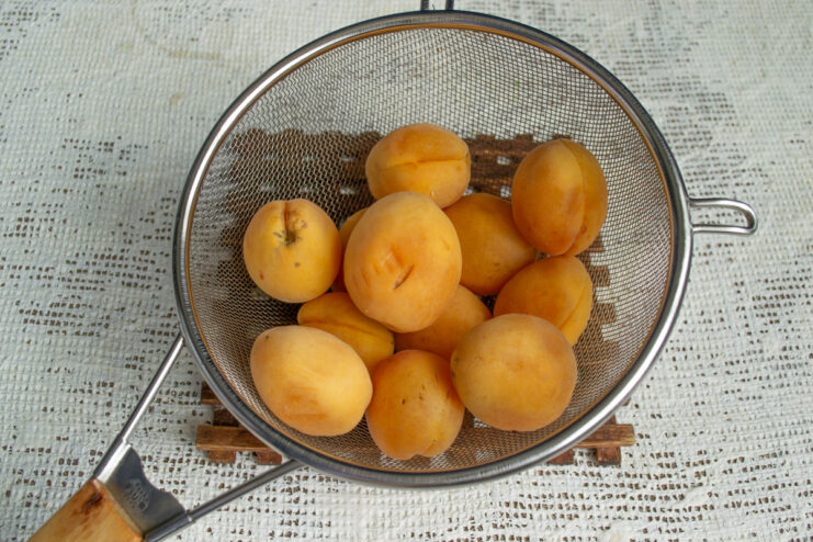 Prepping the apricots Whole ripe apricots resting in a metal sieve.