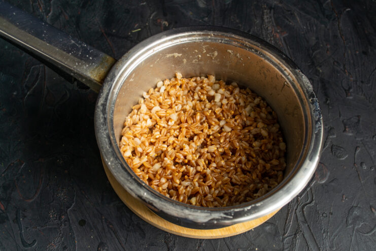 Freshly boiled spelt Perfectly cooked fluffy spelt grains resting in a heavy pot.