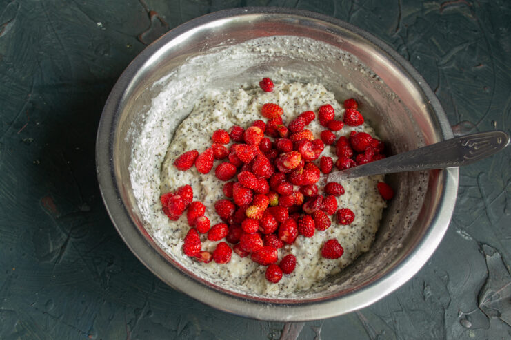 Fresh wild strawberries being folded into the thick muffin batter.