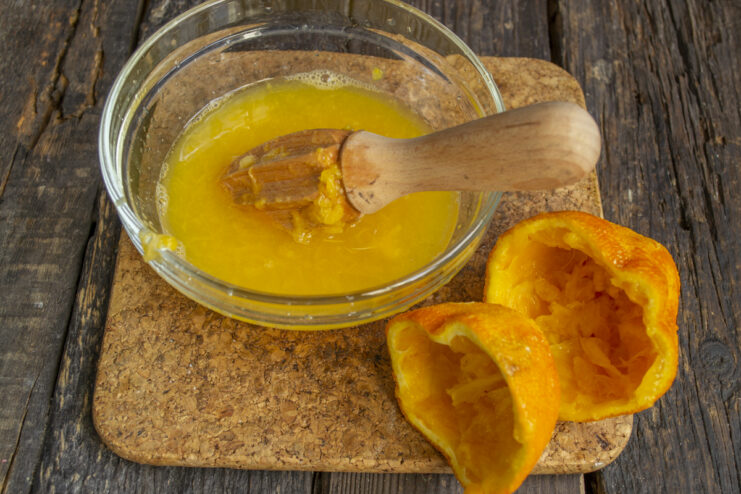 Juicing the Orange Freshly squeezed orange juice in a glass bowl