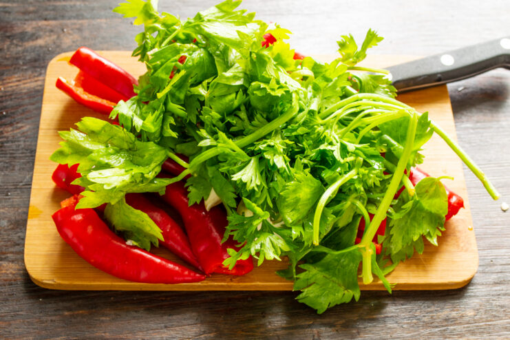 Adding Celery To The Sauce Fresh celery stems, red peppers, and garlic on a board
