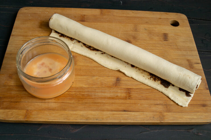 Rolling the pastry log Rolling the filled pastry dough into a tight log.