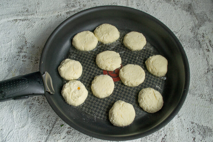 Frying The Syrniki Frying small dough pucks in a skillet until golden brown