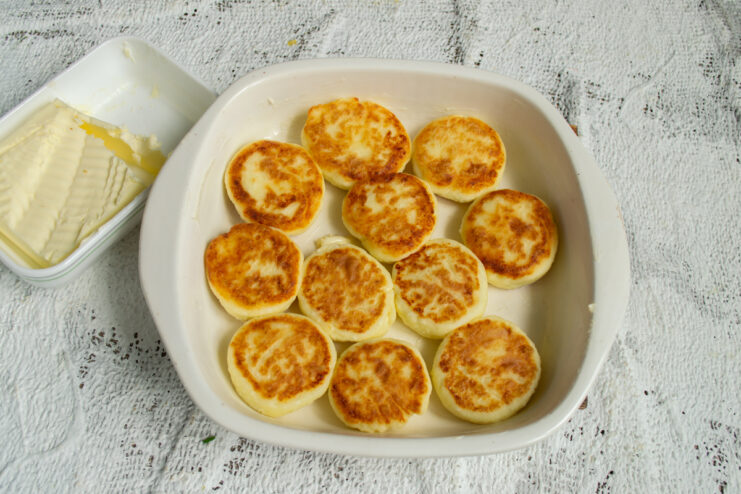 Arranging In The Dish Arranging pan-fried syrniki closely together in a baking dish