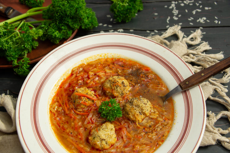 Bowl of fresh cabbage fish soup with meatballs and green parsley.