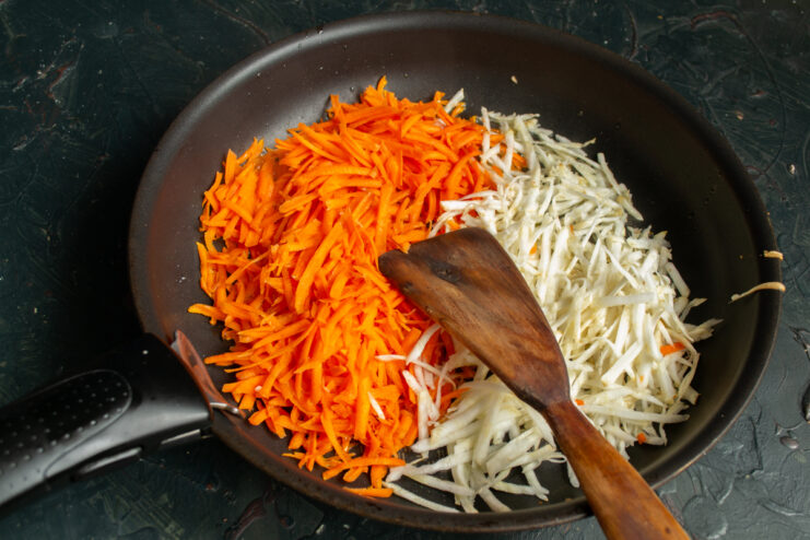 Grated carrots and celery root cooking in a skillet