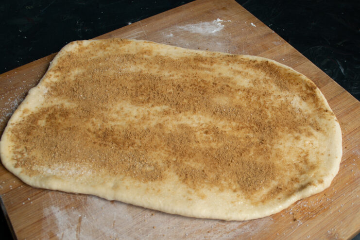 Adding the cinnamon layer Rolled dough evenly sprinkled with a cinnamon and sugar mixture