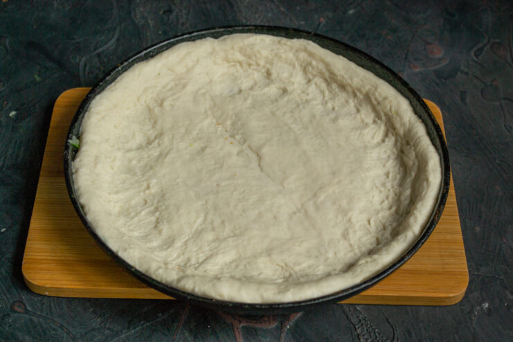 Forming the pie crust Dough spread across the bottom of a cast-iron skillet with raised edges.
