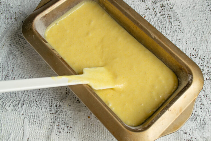 Pouring Into the Pan Cornmeal cake batter spread evenly in a rectangular loaf pan.