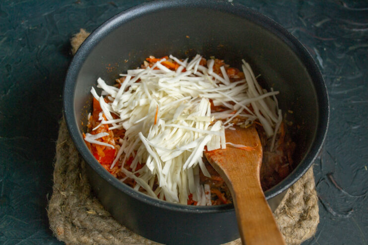 Adding fresh cabbage Thinly shredded fresh cabbage folded into the pot.