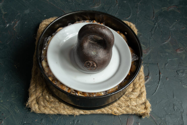 Weighing down the cake Cake pan weighed down with a flat plate and a heavy object on top