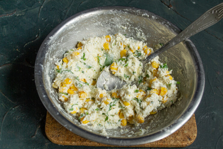 Kneading the dough for even distribution Thoroughly mixed pancake dough with visible spinach and corn