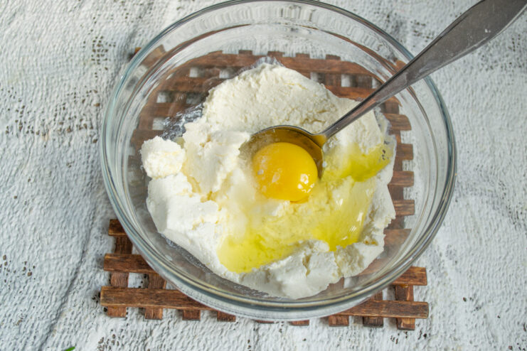 Mixing The Base Ingredients Mixing fresh farmer's cheese, an egg, and salt in a bowl