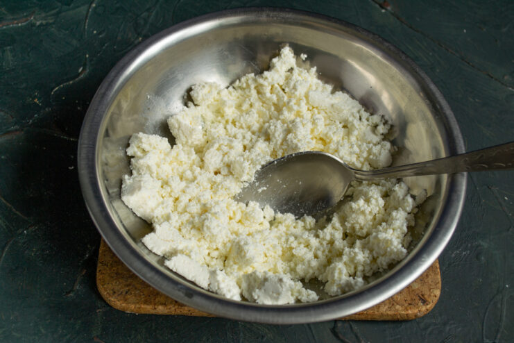 Preparing the cheese for a smooth texture Farmer's cheese in a metal bowl ready to be mashed for pancakes