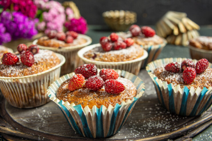 Baked farmer's cheese muffins with wild strawberries and poppy seeds garnished with fresh whole berries.