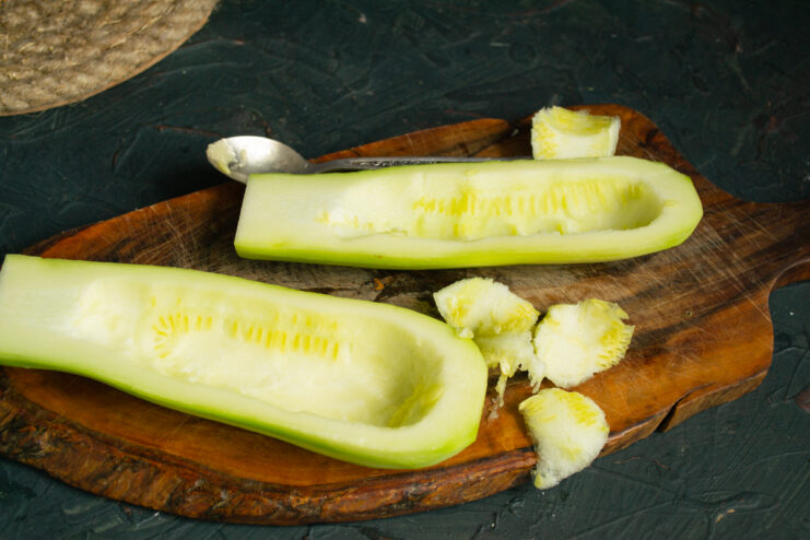 Removing The Core Scooping seeds out of a halved zucchini using a spoon