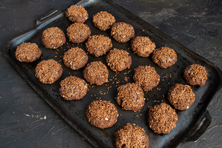 Letting the Glaze Set Decorated chocolate almond cookies resting on a dark baking sheet