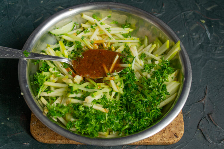 Pouring the aromatic dressing over the fresh vegetables in a bowl